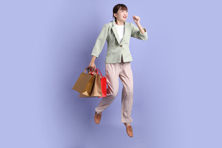 Young asian Businesswoman in formal outfit with gesture of holding shopping bag, Jumping isolated on purple background. Gen Z, internship, Career, Officeの写真素材