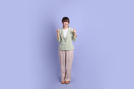 A young asian Businesswoman in formal outfit with gesture of thumbs up, ok or confirm isolated on purple background. Gen Z, internship, Career, Officeの写真素材