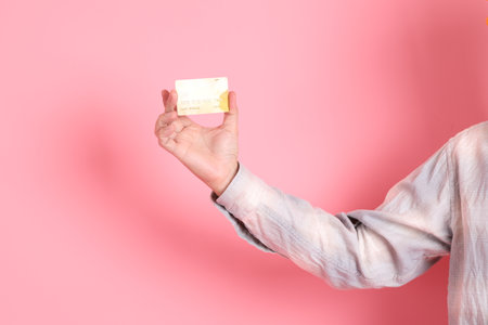 Asian senior man in formal and casual white shirts with gesture of hand Holding credit card isolated on pink background.の写真素材