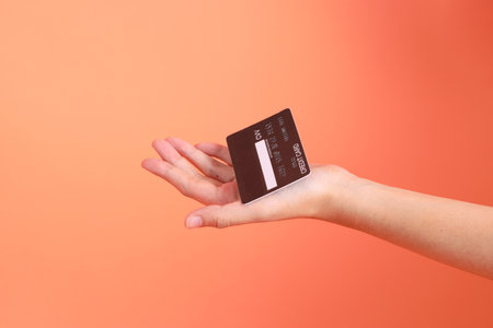 Asian senior man in Green plaid casual clothes wearing glasses with gesture of Holding card isolated on orange background. Tourist, Smart casual.の写真素材