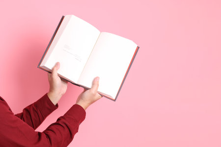 asian senior man in formal and casual red shirts with gesture of hand holding a book isolated on pink background.の写真素材