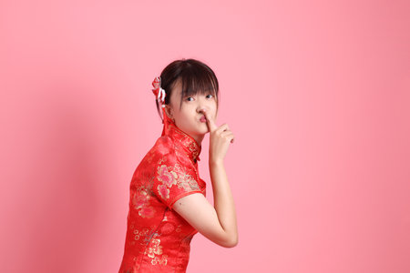 Happy Chinese new year. Asian Chinese woman wearing red traditional cheongsam qipao with gesture of Mouth close, Silent gesture isolated on pink background. Gen Zの写真素材