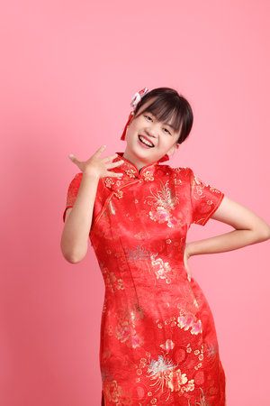 Happy Chinese new year. Asian Chinese woman wearing red traditional cheongsam qipao with gesture of standing and smile isolated on pink background. Gen Zの写真素材