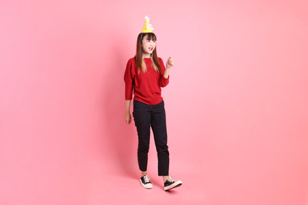 young female asian woman in red casual t-shirt with gesture of holding birthday cake isolated on pink background. Gen Z, walkingの写真素材