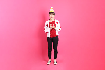 Asian woman in red t-shirt or casual clothes, red heart-shaped shirt jacket with gesture of holding birthday cake isolated on pink background. Gen Z. clapping handsの写真素材