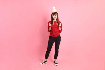 young  female asian woman in red casual t-shirt with gesture of Holding birthday cake isolated on pink background. Gen Z. Heart-shaped, mini heart, love.の写真素材