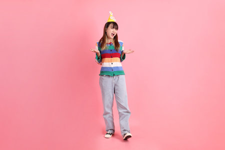Asian woman with colorful rainbow winter clothes, casual look, birthday hat with gesture of Pity, Sorry, not a big deal isolated on pink background. Gen Z.の写真素材
