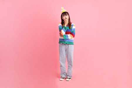 Asian woman with colorful rainbow winter clothes , casual look, birthday hat with gesture of thinking isolated on pink background. Gen Z,の写真素材