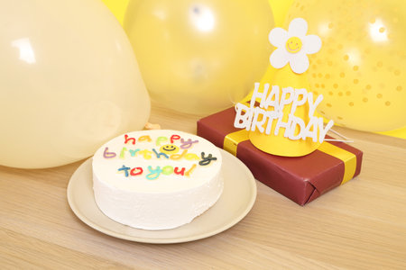 Birthday Cake with  Happy Birthday text, Party hat , Gift box and balloon isolated on yellow background, Happy Birthday Concept. Familyの写真素材