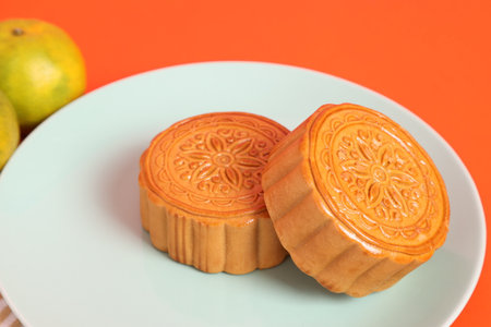 Traditional Chinese dessert Moon cake or Chinese pastry isolated on pink and orange background. Chinese traditional Mid-Autumn Festival, Moon Festival.の写真素材