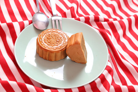 Traditional Chinese dessert Moon cake or Chinese pastry on red stripes tablecloth isolated on pink background. Chinese traditional Mid-Autumn Festival, Moon Festival.の写真素材