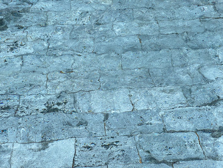 Abstract texture of stone pavement seen through rippling water. The light distortion creates a natural wave pattern on the stone surface, ideal for background, design, or artistic use.の写真素材