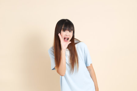 Young Asian woman wearing a light blue polo shirt, shouting, holding megaphone against a plain beige background. College student, Gen Z, Summerの写真素材