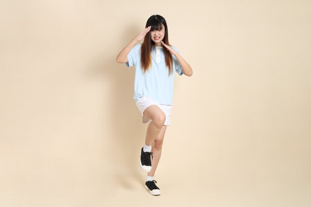 Young Asian woman wearing a light blue polo shirt, and white shorts, Fighting against a plain beige background. College student, Gen Z, Summerの写真素材