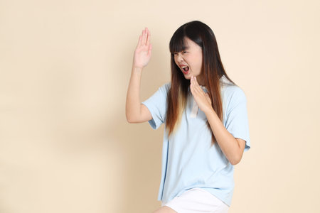 Young Asian woman wearing a light blue polo shirt, and white shorts, Fighting against a plain beige background. College student, Gen Z, Summerの写真素材