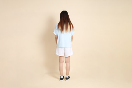 Young Asian woman wearing a light blue polo shirt, and white shorts, Walking against a plain beige background. College student, Gen Z, Summerの写真素材
