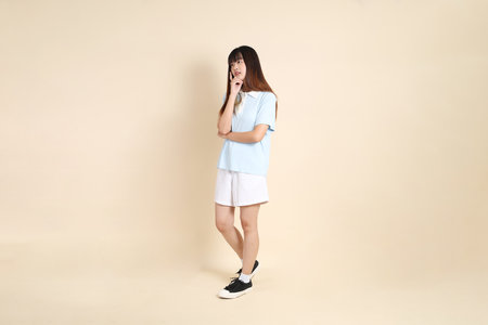 Young Asian woman wearing a light blue polo shirt, and white shorts, Walking against a plain beige background. College student, Gen Z, Summerの写真素材