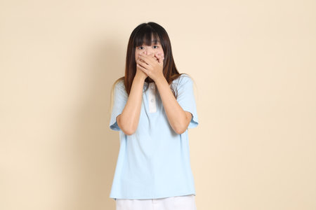 Young Asian woman wearing a light blue polo shirt, and white shorts, smelling, cover nose against a plain beige background. College student, Gen Z, Summerの写真素材