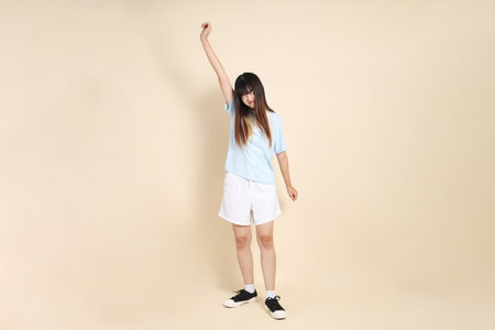 Young Asian woman wearing a light blue polo shirt, and white shorts, against a plain beige background. College student, Gen Z, Summerの写真素材