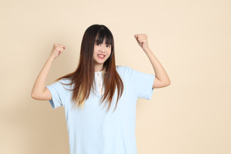 Young Asian woman wearing a light blue polo shirt, healthy, strong against a plain beige background. College student, Gen Z, Summerの写真素材