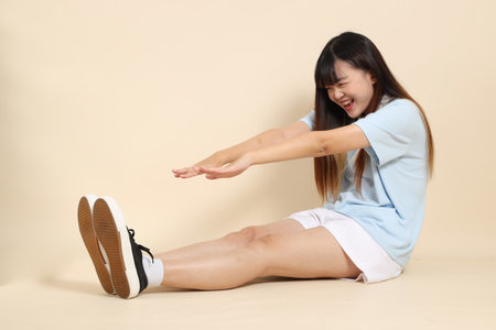 Young Asian woman wearing a light blue polo shirt, and white shorts, exercise against a plain beige background. College student, Gen Z, Summerの写真素材