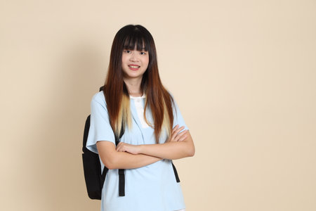 Asian woman wearing blue polo shirt, carrying school backpack against a plain beige background. Gen Z,の写真素材