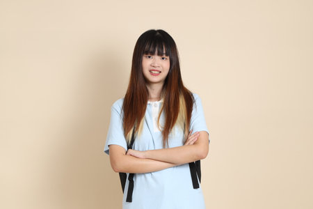 Asian woman wearing blue polo shirt, carrying school backpack against a plain beige background. Gen Z,の写真素材