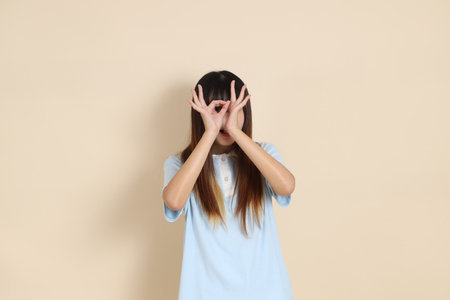 Medium shot of a young Asian woman wearing a light blue polo shirt, against a plain beige background. College student, Gen Zの写真素材