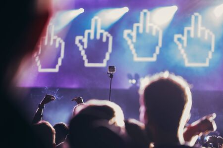 Stage lights and crowd of audience with hands raised at a music festival. Fans enjoying the party vibes.の写真素材