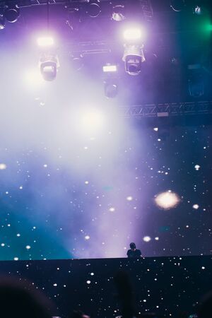Stage lights and crowd of audience with hands raised at a music festival. Fans enjoying the party vibes.の写真素材