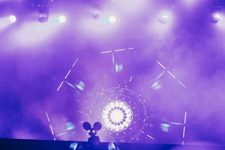 Stage lights and crowd of audience with hands raised at a music festival. Fans enjoying the party vibes.の写真素材