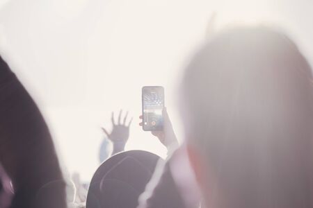 Stage lights and crowd of audience with hands raised at a music festival. Fans enjoying the party vibes.の写真素材