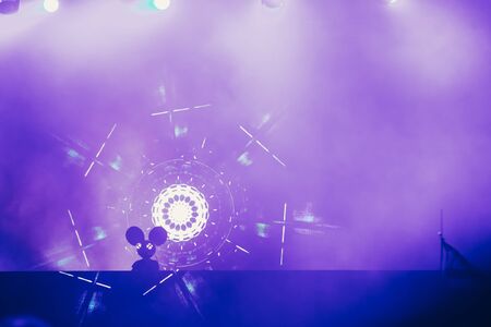Stage lights and crowd of audience with hands raised at a music festival. Fans enjoying the party vibes.の写真素材