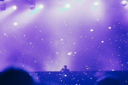 Stage lights and crowd of audience with hands raised at a music festival. Fans enjoying the party vibes.の写真素材