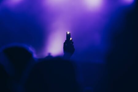 Stage lights and crowd of audience with hands raised at a music festival. Fans enjoying the party vibes.の写真素材