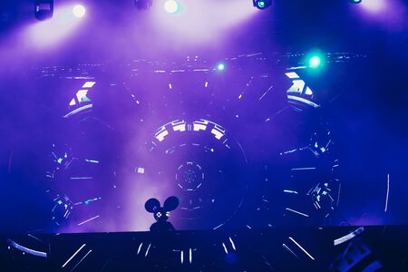 Stage lights and crowd of audience with hands raised at a music festival. Fans enjoying the party vibes.の写真素材