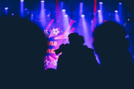 Stage lights and crowd of audience with hands raised at a music festival. Fans enjoying the party vibes.の写真素材