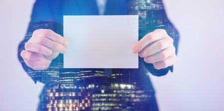 Double exposure of businesswoman in suit holding blank paper for text.の写真素材