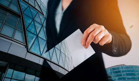 Double exposure image of voter putting ballot into voting box and buildings. Business and election concept. の写真素材
