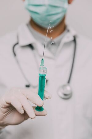 Male doctor with syringe and stethoscope.  Coronavirus epidemic concept. の写真素材