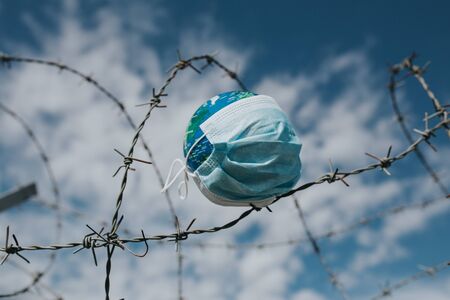 Surgical mask on Earth globe. Epidemics concept. World infected with Covid-19 / Coronavirus.の写真素材