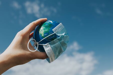 Surgical mask on Earth globe. Epidemics concept. World infected with Covid-19 / Coronavirus.の写真素材