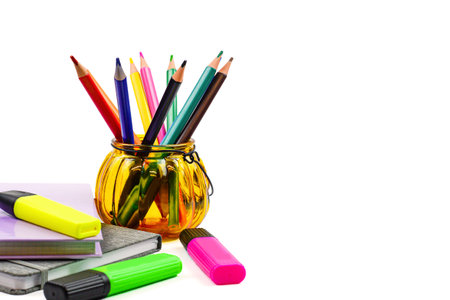 Colorful crayons and pens in glass jar on white backgroundの写真素材
