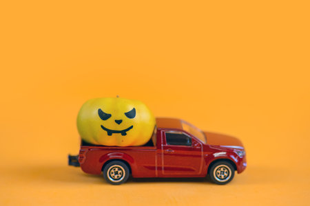 Halloween pumpkin and car toy on orange background. Halloween concept.の写真素材