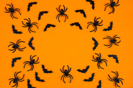 Halloween background with black spiders on orange background. Flat lay, top view.の写真素材
