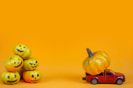 Halloween pumpkins and toy car on orange background. Copy space.の写真素材