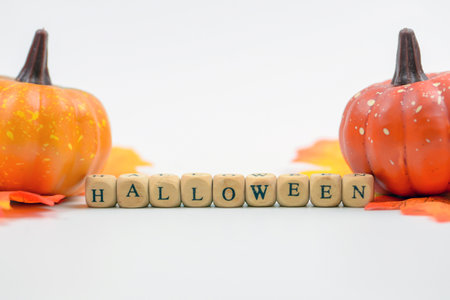 Halloween word made of wooden cubes and pumpkins on white backgroundの写真素材