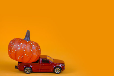 Halloween pumpkins and red car on orange background with copy spaceの写真素材