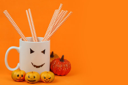Cup of coffee with straws and pumpkins on orange backgroundの写真素材