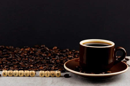Coffee beans and cup of black coffee on a gray backgroundの写真素材
